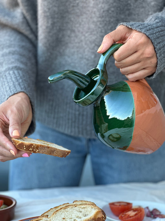 photo of olive oil being poured onto a slice of bread in a traditional catalan olive oil pourer